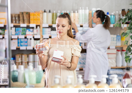 Pregnant girl chooses pills at pharmacy 126144579