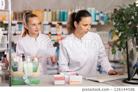 Two female pharmacists checking prescription on computer Two female pharmacists checking prescription on computer 126144586
