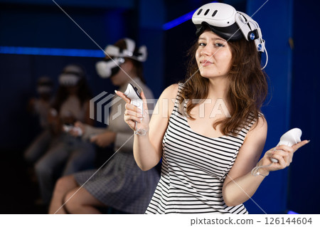 Excited teenage girl with gaming controllers and VR glasses Excited teenage girl with gaming controllers and VR glasses 126144604