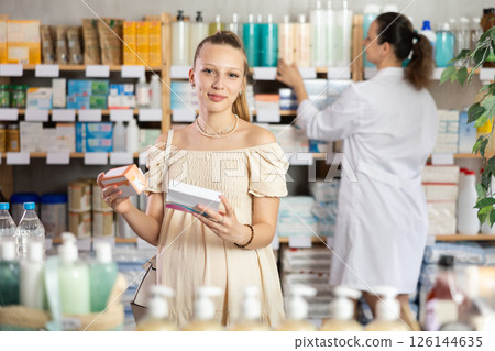 Pregnant girl chooses pills at pharmacy 126144635