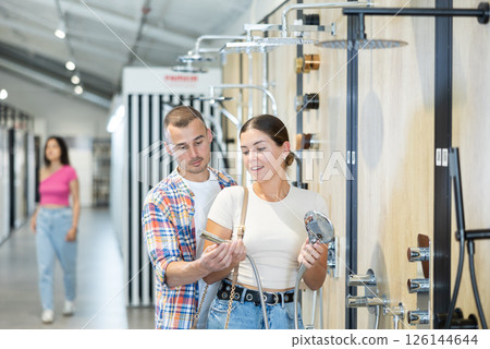 Interested couple choosing showerheads in plumbing supply store 126144644