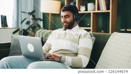 Headphones, typing and man with laptop for remote work, audio and copywriter editing ad campaign in home. Living room, computer and happy freelancer with music for content writer with article or blog 126144674