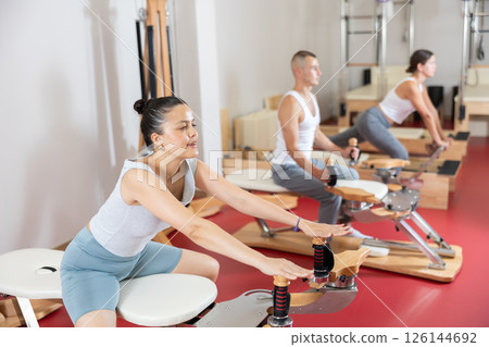 Young woman stretching her arms using pilates machine Young woman stretching her arms using pilates machine 126144692