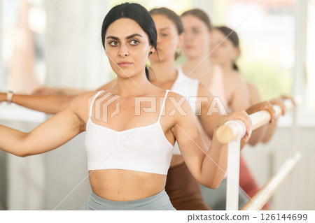 Young girl practicing plie position holding by ballet barre in group 126144699