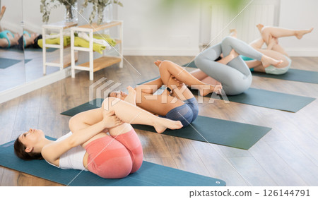 Girl teaches yoga lesson, shows students technique of performing Supt kapotasana asana Girl teaches yoga lesson, shows students technique of performing Supt kapotasana asana 126144791