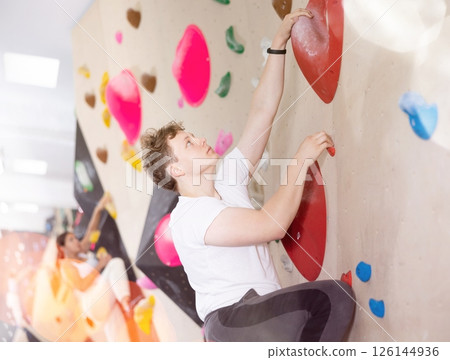 Alpinist practicing rock-climbing on artificial boulder without safety belts Alpinist practicing rock-climbing on artificial boulder without safety belts 126144936