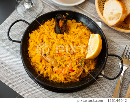 Spanish rice dish paella tinted with saffron. Prepared with olive oil and seafood 126144942