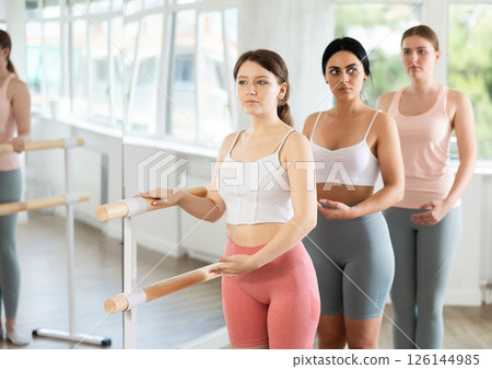 Young girl practicing first position holding by ballet barre 126144985