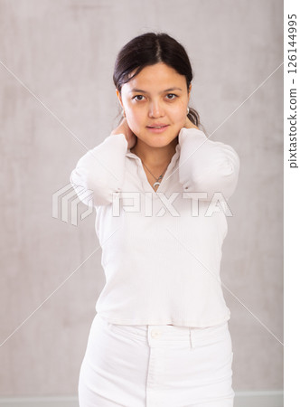 Portrait of an attractive young asian girl in a white trouser suit on gray background Portrait of an attractive young asian girl in a white trouser suit on gray background 126144995