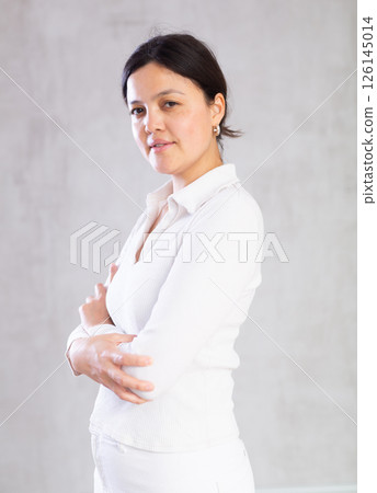 Young slender woman in light casual clothes poses with arms crossed on chest. Young slender woman in light casual clothes poses with arms crossed on chest. 126145014