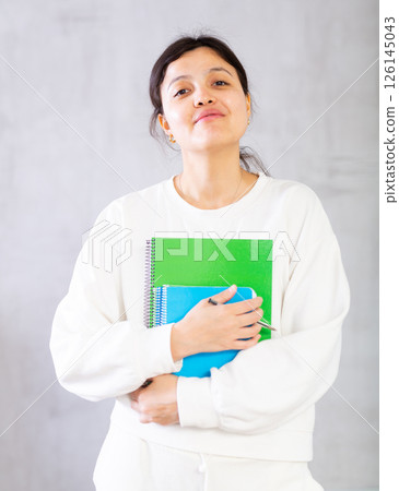 Smiling young female tutor or college student with workbooks 126145043