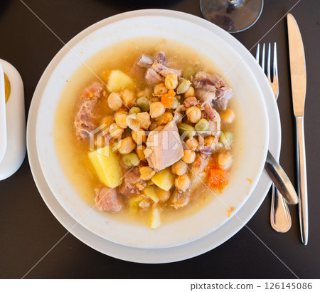 Popular dish of Spanish cuisine is Cocido de garbanzos, made from meat, vegetables and chickpeas, closeup 126145086