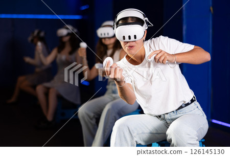 Expressive girl in VR goggles having fun in virtual reality room 126145130