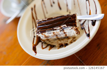 There is small piece of white ice cream on plate, decorated with chocolate chips and icing There is small piece of white ice cream on plate, decorated with chocolate chips and icing 126145167