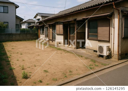 A Showa-era tenement house and a vacant lot with few weeds in front of it 126145295