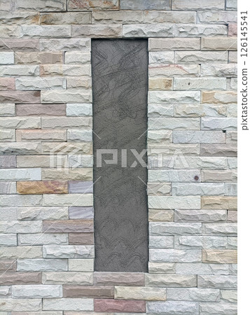 A stone wall with vertical gray panel displays strength and texture, creating modern and inviting architectural element A stone wall with vertical gray panel displays strength and texture, creating modern and inviting architectural element 126145541