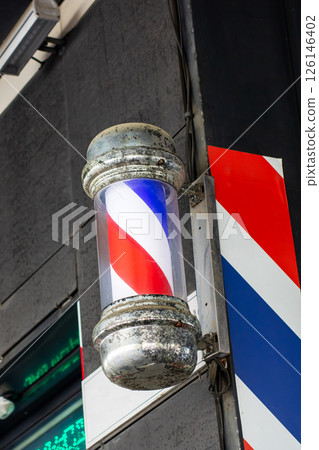 A traditional barber pole featuring red, white, and blue stripes 126146402