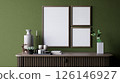 A modern interior scene featuring a green wall, decorative empty frames, a vase, candles, and small plants on a stylish wooden console table. 3d rendering. 126146927