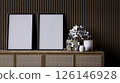 A modern interior scene featuring a wooden console with empty frames and decorative flowers against a textured wall. 126146928