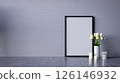 A minimalistic decor featuring a blank frame, white flowers in a vase, and candles against a textured gray wall. 3d rendering blank frame on wall for copy space advertising. 126146932