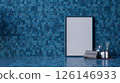A modern interior featuring a blue tiled wall with a blank frame, towels, and decorative bottles, creating a serene and stylish atmosphere. 126146933