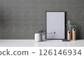 A modern interior featuring a textured wall, minimalist vases, a blank picture frame. 3d rendering. 126146934