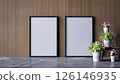 A modern interior scene featuring two empty picture frames on a textured wall, complemented by potted flowers on a marble floor. 3d rendering. 126146935