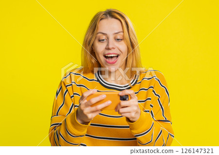 Happy woman playing racing drive simulator shooter video games on smartphone celebrate victory win 126147321