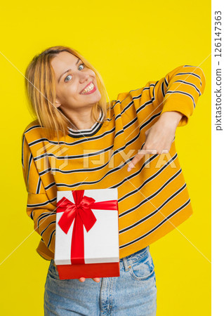 Smiling woman presenting birthday gift present box stretches out hands, promotion discount sale 126147363