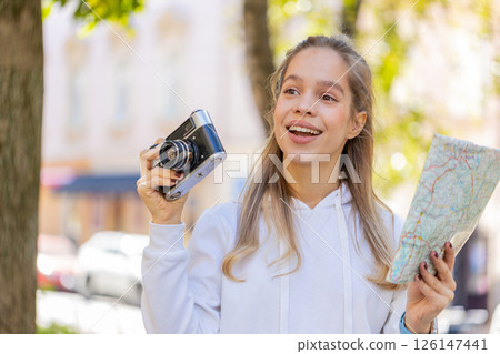Caucasian young woman tourist looking at city map, making photo pictures on retro vintage camera 126147441
