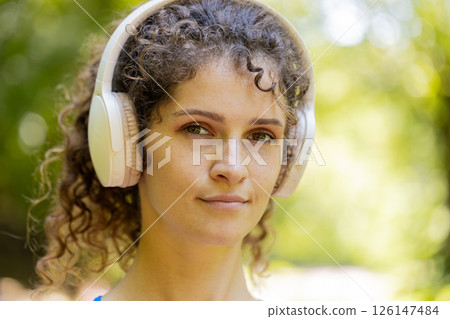 Close-up face portrait of athletic fitness sport runner girl listening music song in headphones 126147484