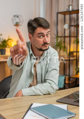 Displeased Caucasian young man freelancer shake finger No sitting at home office desk in living room Displeased Caucasian young man freelancer shake finger No sitting at home office desk in living room 126147495