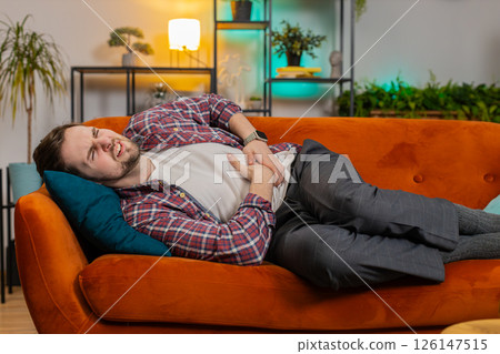 Man lying on sofa feeling sudden strong abdominal stomach ache gastritis problem poisoning diarrhea Man lying on sofa feeling sudden strong abdominal stomach ache gastritis problem poisoning diarrhea 126147515
