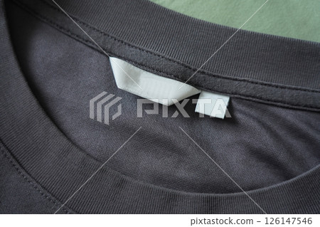 Close up of blank white clothing care label on black shirt fabric background. Close up of blank white clothing care label on black shirt fabric background. 126147546