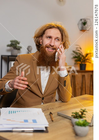 Business man freelancer sits at office answering to client on mobile smartphone call conversation Business man freelancer sits at office answering to client on mobile smartphone call conversation 126147678