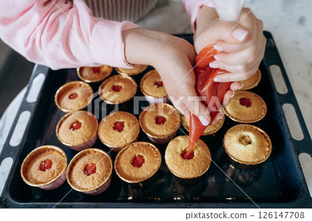 Decorated Cupcakes with Strawberry Filling Action Shot 126147708