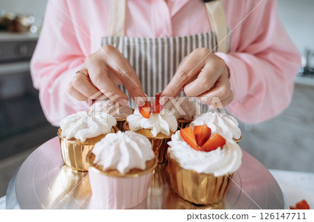 Decorating Cupcakes with Strawberries and Whipped Cream 126147711