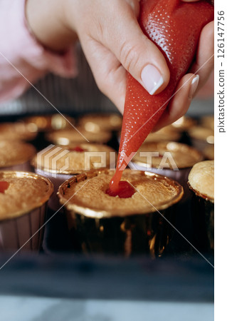 Filling Cupcakes with Strawberry Topping for Dessert 126147756