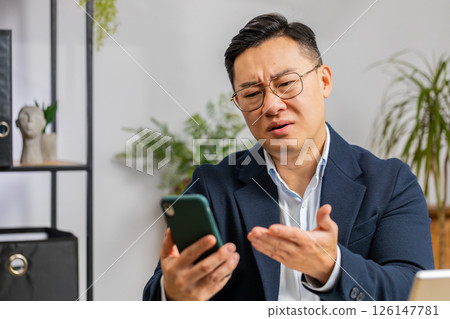 Asian office business man use smartphone surprised by bad news, fortune loss, fail, lottery results Asian office business man use smartphone surprised by bad news, fortune loss, fail, lottery results 126147781