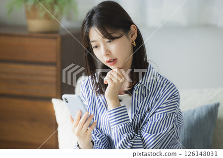 A young woman with a troubled face looking at her smartphone 126148031