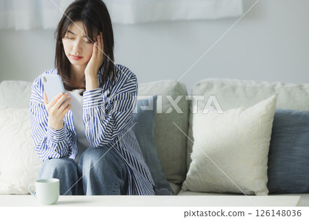 A young woman with a troubled face looking at her smartphone 126148036