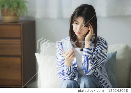 A young woman with a troubled face looking at her smartphone 126148038
