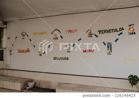 Vibrant multilingual welcome wall mural with international greetings and travel icons at Lisbon train station interior colorful artistic decoration for cultural diversity. High quality photo 126148425