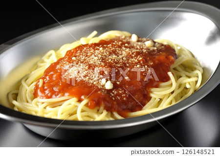Meat sauce pasta topped with grated cheese photographed against a black background 126148521