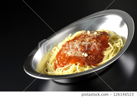 Meat sauce pasta topped with grated cheese photographed against a black background 126148523