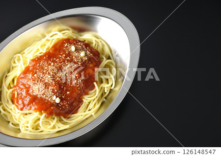 Meat sauce pasta topped with grated cheese photographed against a black background 126148547