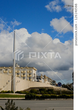 Tall modern monument with vertical white pillar in residential neighborhood of Fatima Portugal with surrounding buildings under blue sky and clouds. High quality photo Tall modern monument with vertical white pillar in residential neighborhood of Fatima Portugal with surrounding buildings under blue sky and clouds. High quality photo 126148566
