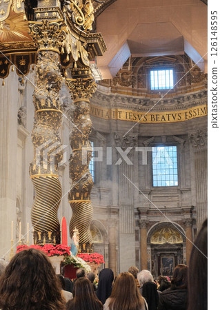 Ornate Baldachin canopy over Papal Altar in Saint Peters Basilica Vatican City designed by Gian Lorenzo Bernini with twisted bronze columns red floral decorations and Latin inscriptions under grand 126148595