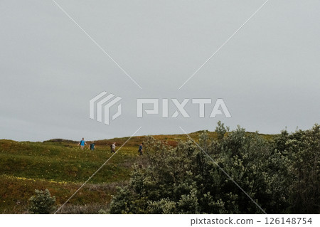 Hikers walking along scenic coastal trail at Cabo da Roca Sintra Portugal with grassy cliffs overlooking Atlantic Ocean under cloudy sky westernmost mainland Europe outdoor travel landscape. High Hikers walking along scenic coastal trail at Cabo da Roca Sintra Portugal with grassy cliffs overlooking Atlantic Ocean under cloudy sky westernmost mainland Europe outdoor travel landscape. High 126148754