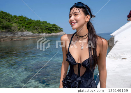 一位身穿黑色泳衣的美麗日本女子在藍天和夏日海灘下微笑 126149169
